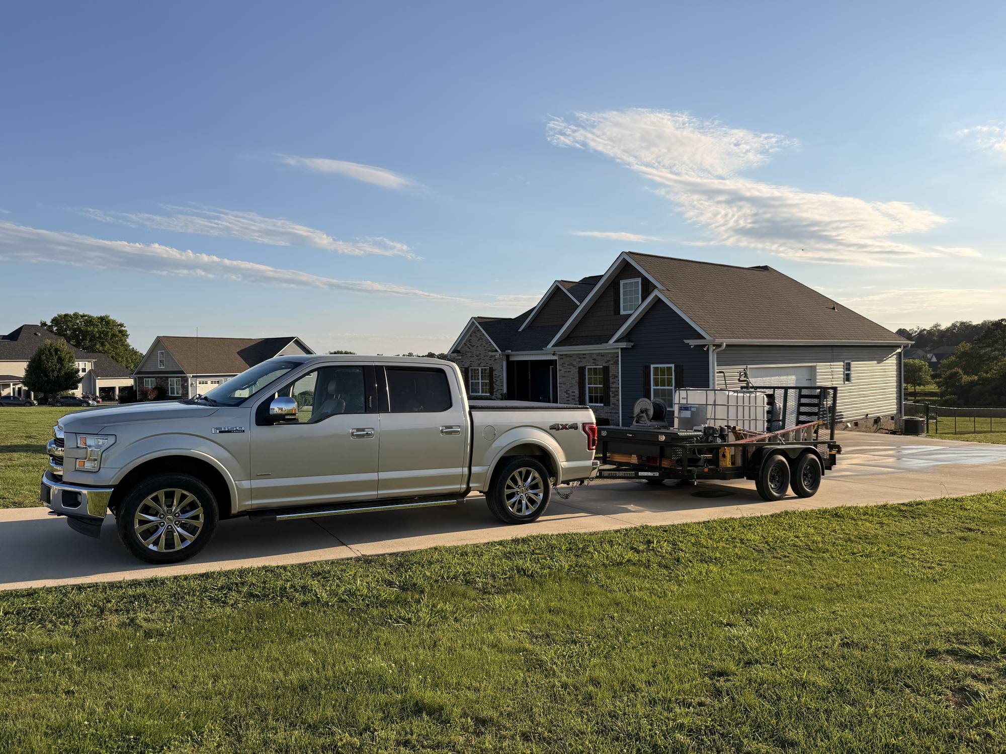 Tricolor Pressure Washing truck and equipment trailer parked at a client's home